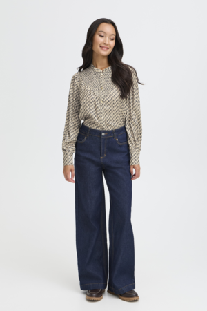 Woman wearing a patterned blouse and blue jeans on a white background